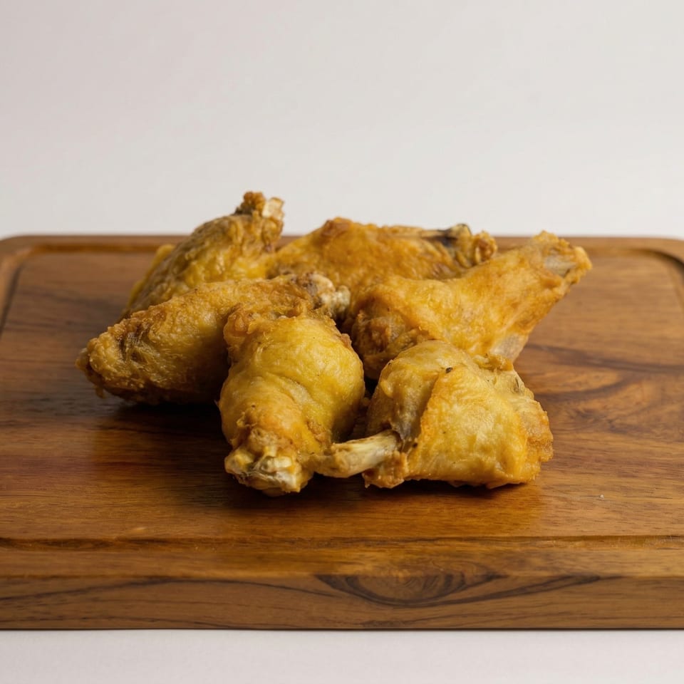 Golden brown fried chicken wings piled on a rustic wooden cutting board.